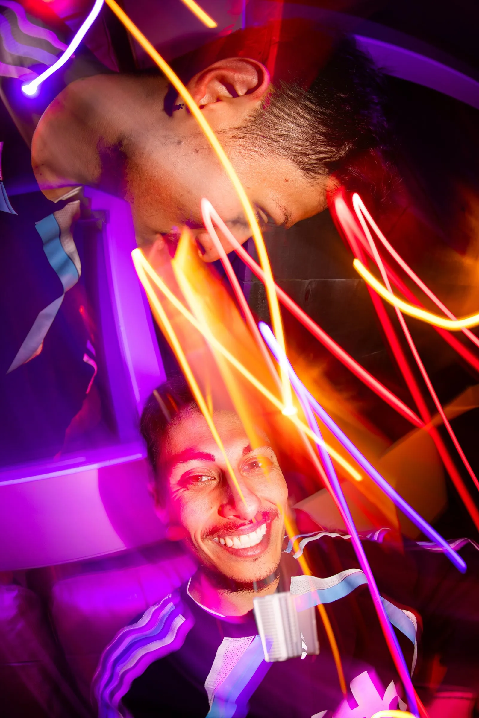 Long-exposure light trails swirling around two smiling faces at a party