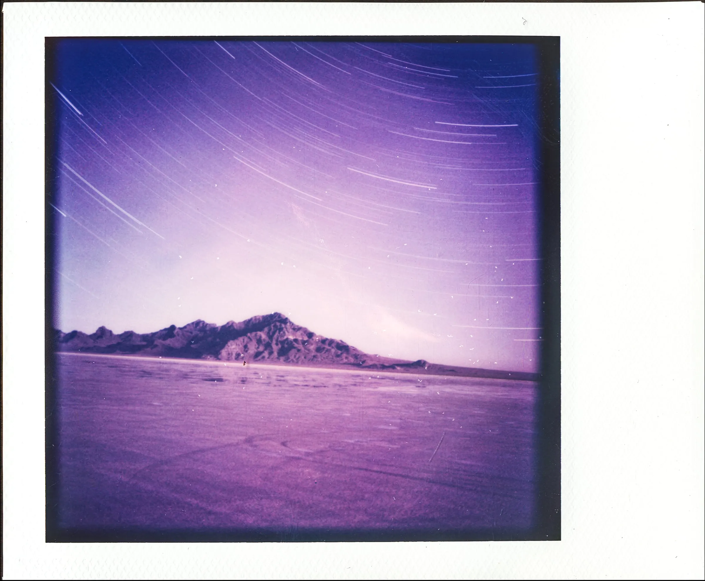 Polaroid of star trails over a desert mountain on the salt flats