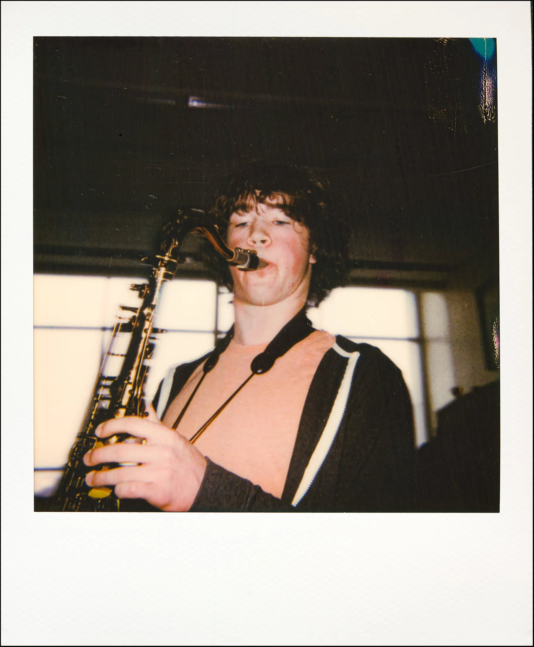 Polaroid of a saxophonist mid-solo in front of bright windows