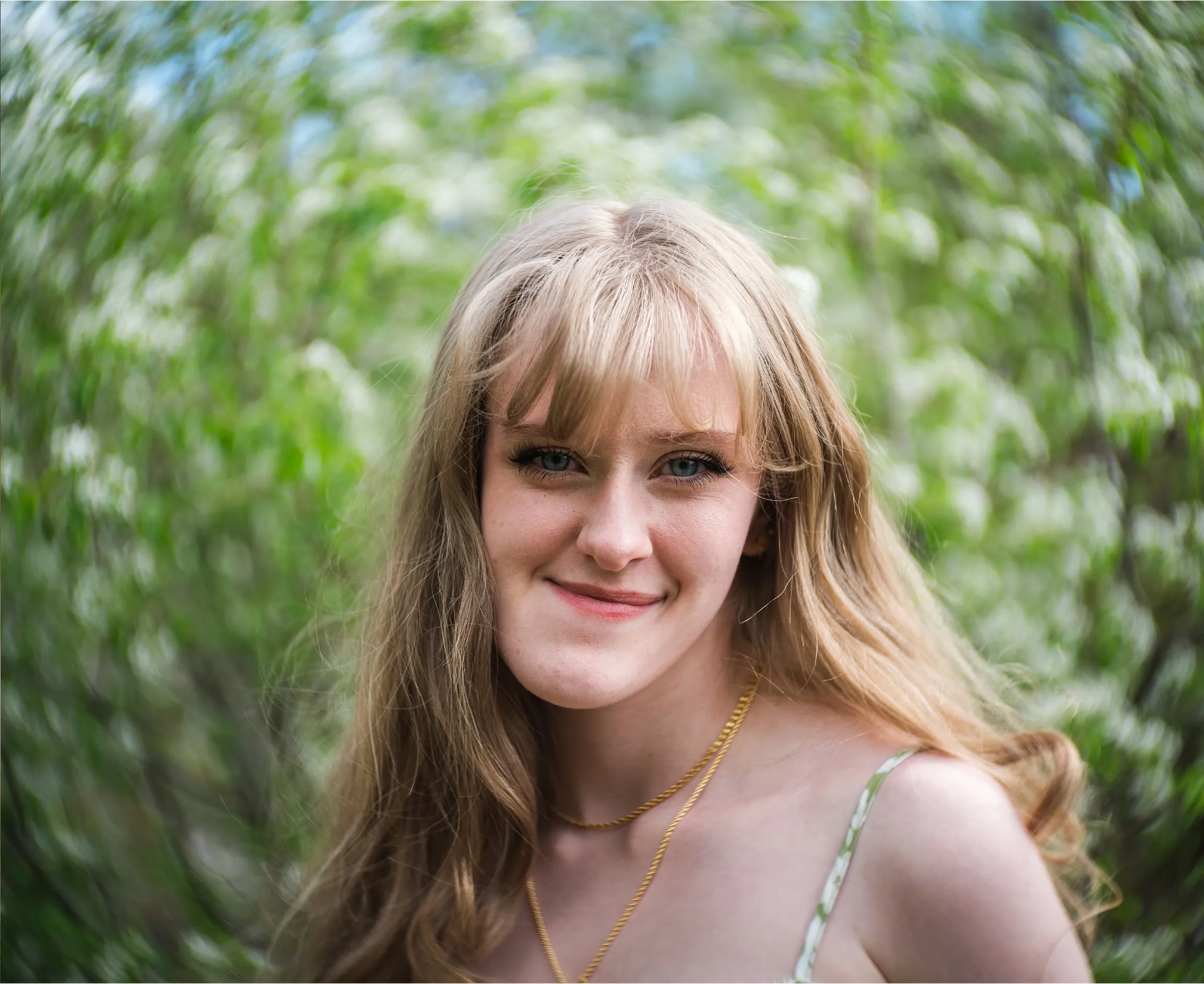 Senior portrait of a smiling woman ringed by swirling blossom bokeh