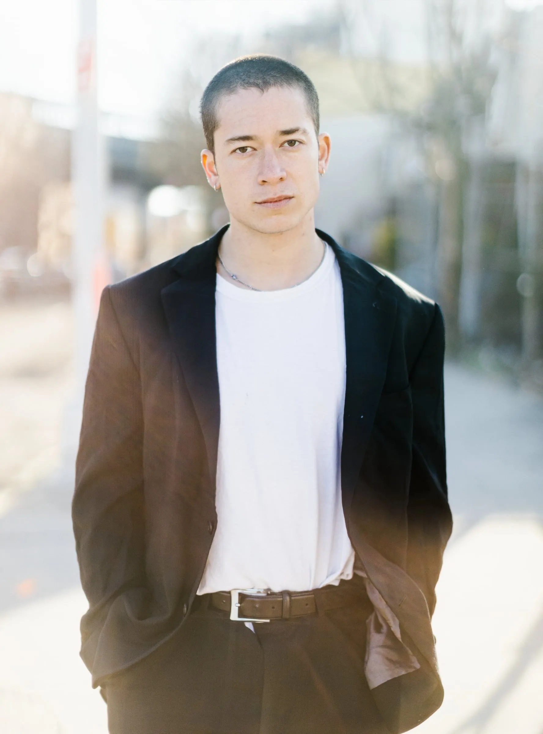 Portrait of a man in an oversized blazer on a sunlit sidewalk