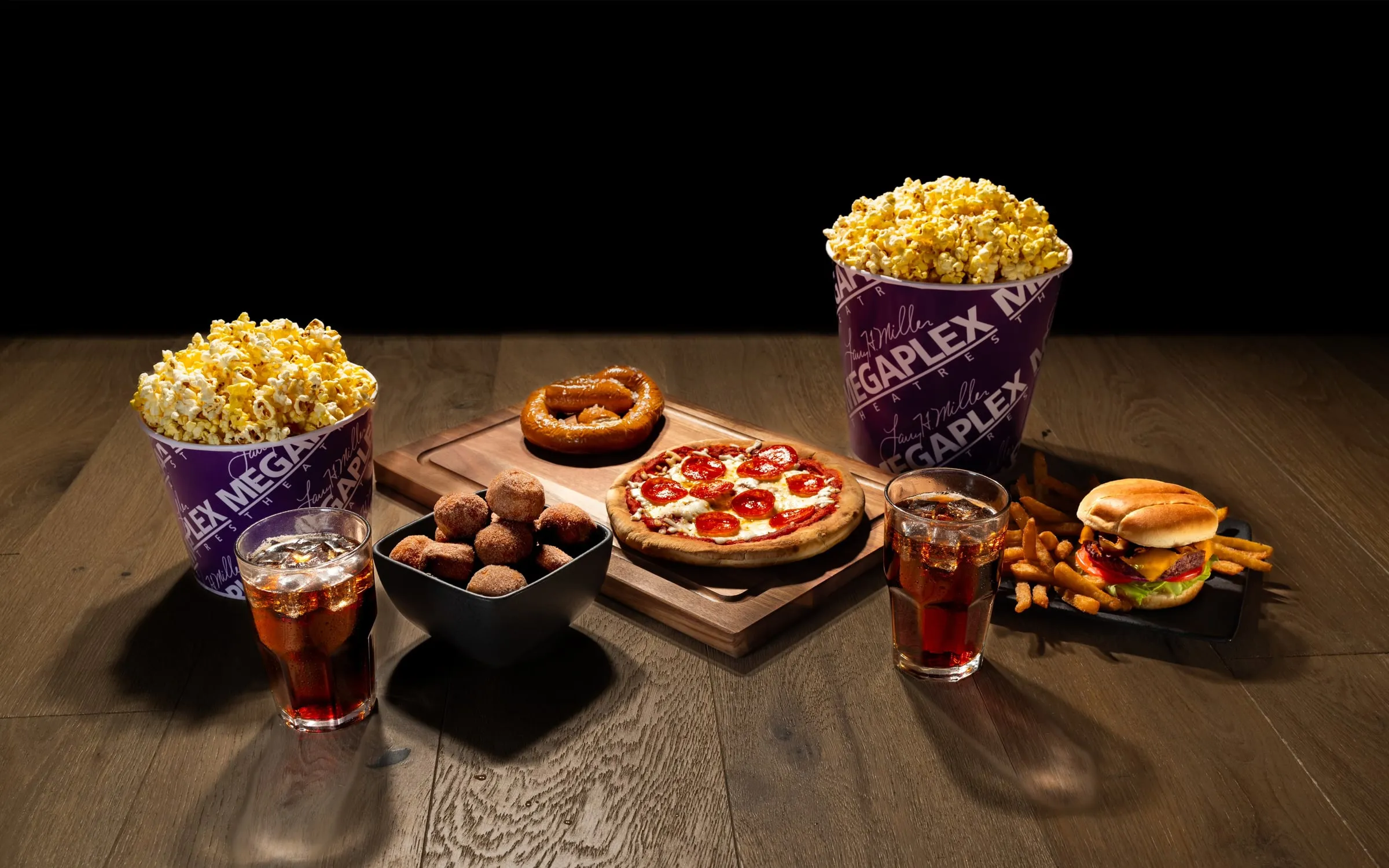 Theater concessions spread: popcorn buckets, pizza, pretzel, burger, and sodas on wood