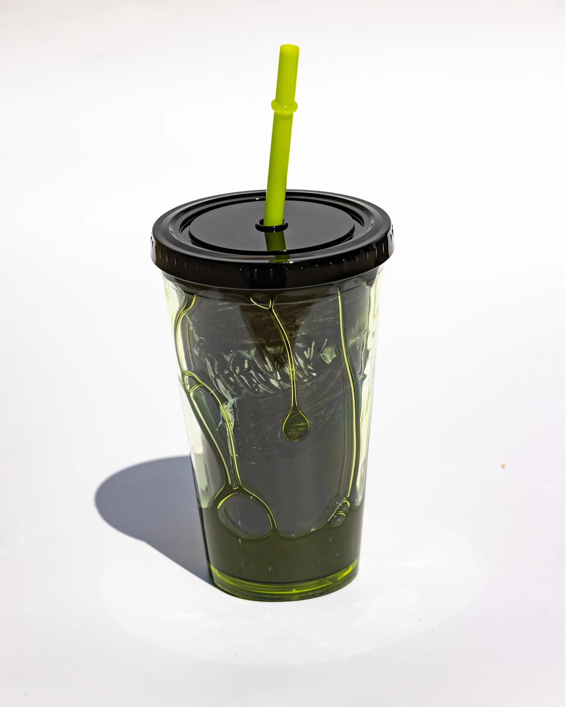 Green translucent cup with syrup drips and a bright green straw