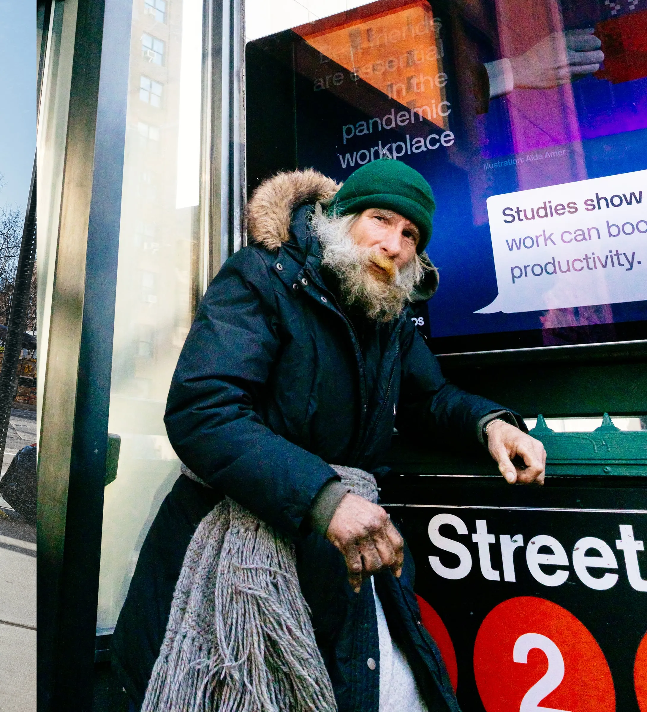 Bearded man in a green beanie beside a subway entrance ad